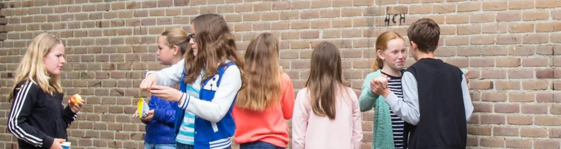 Een groep meisjes die voor een bakstenen muur staan en zich tijdens hun opleiding aan de gedragsregels hielden. School en Veiligheid