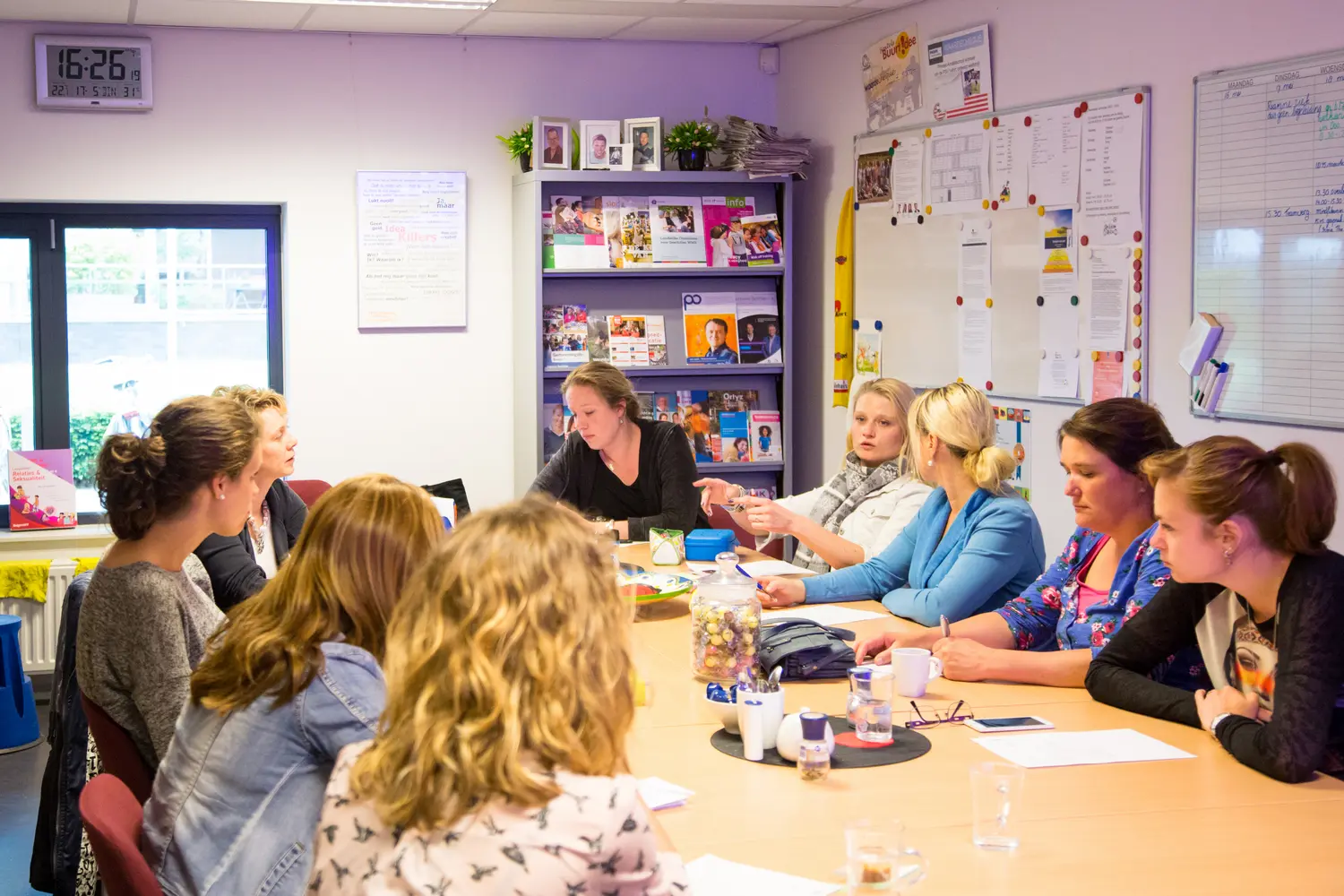 Een groep schoolmedewerkers zit rond een tafel en bespreekt de implementatie van een nieuwe gedragscode. School en Veiligheid