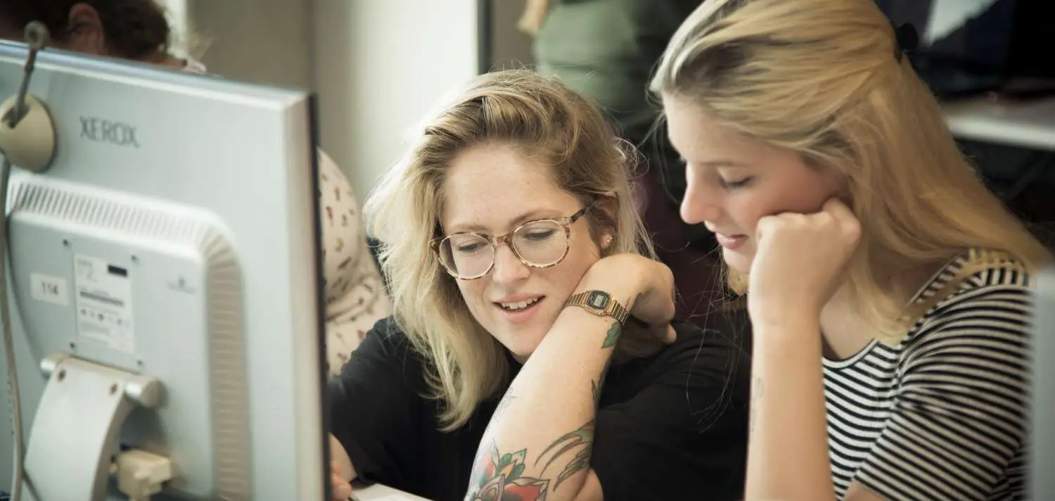 Twee vrouwen bezig met vertrouwenswerk, kijkend naar een computerscherm. School en Veiligheid