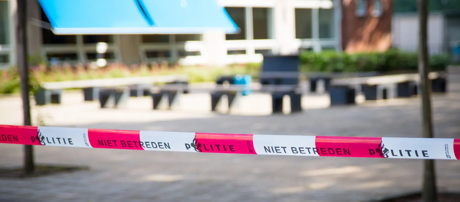 Een rood-witte waarschuwingstape op een trottoir, die wijst op een potentiële dreiging. School en Veiligheid