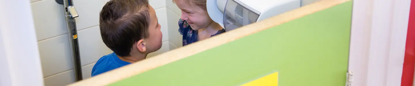 Een kind staat voor een spiegel in een badkamer en observeert onschuldig hun spiegelbeeld. School en Veiligheid