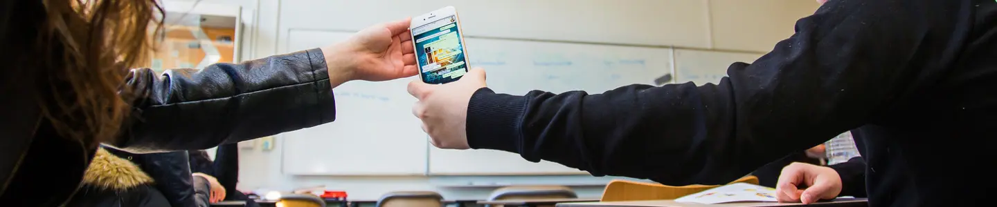 Een persoon die een mobiele telefoon vasthoudt voor een spiegel. School en Veiligheid