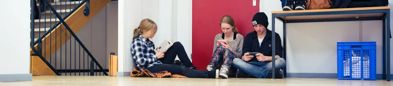 Een groep mensen zit op een bankje in de gang en is verdiept in een gesprek. School en Veiligheid