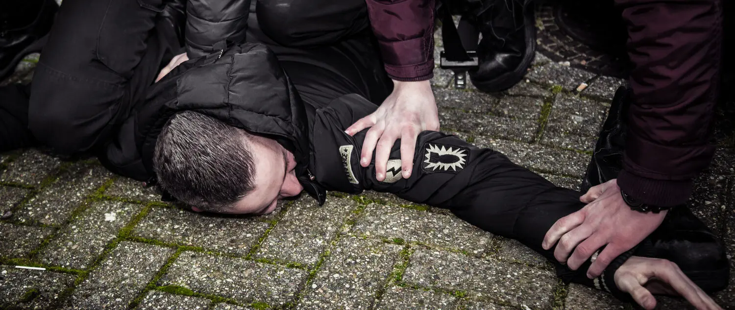 Een man die in een schoolomgeving op de grond ligt met zijn handen op zijn knieën en demonstreert werken aan een intrinsiek integer gedrag. School en Veiligheid