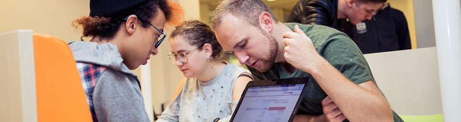 Een groep mensen voerde een discussie rond een laptop in een kantoor. School en Veiligheid