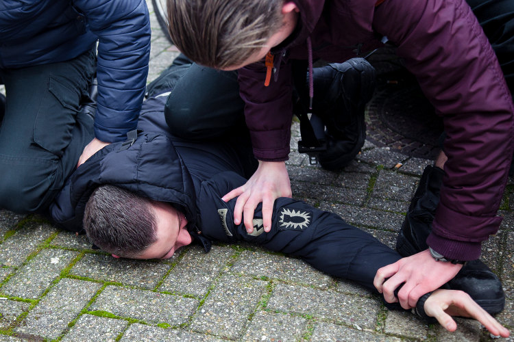 Een man die agressief gedrag vertoont terwijl hij op de grond ligt in een mbo-setting. School en Veiligheid