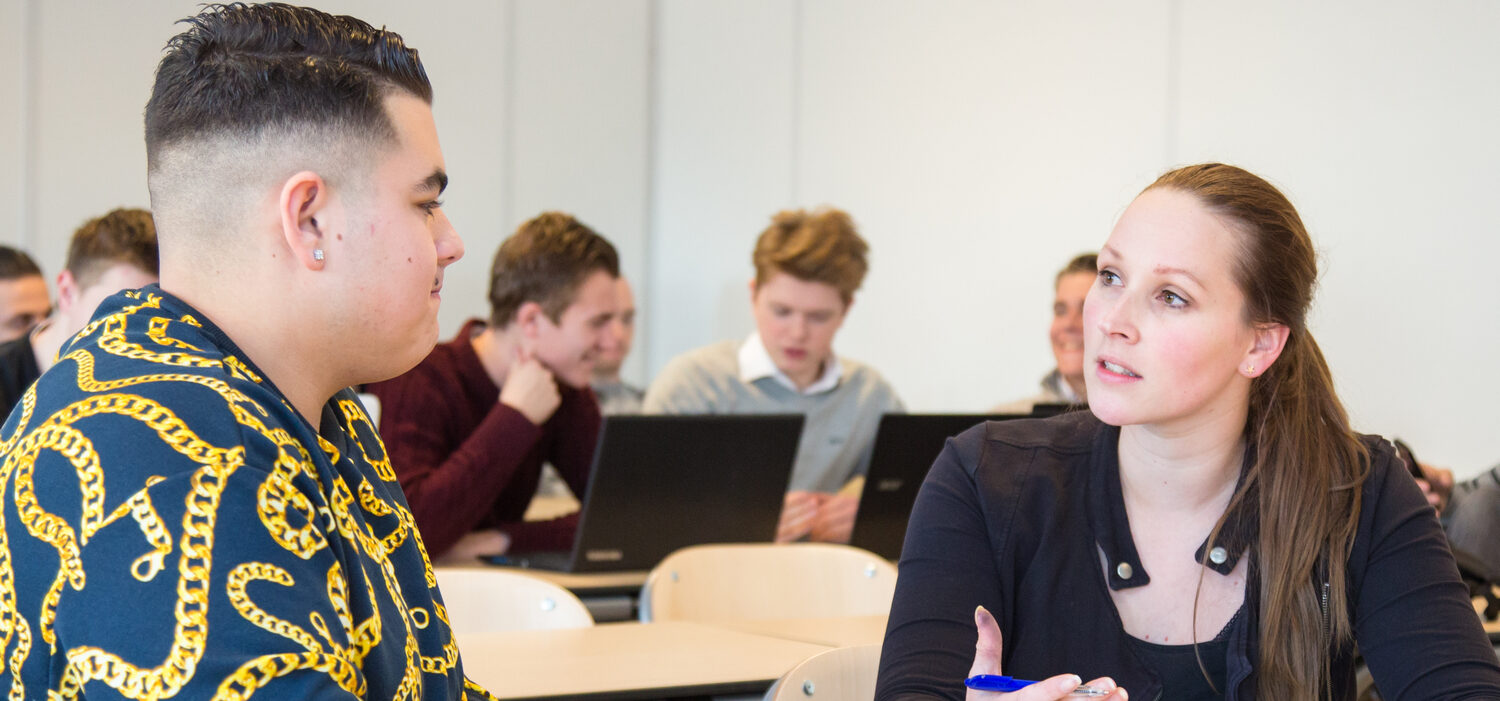 Een groep jongere mensen in een klaslokaal die met elkaar praten, wat aanleiding geeft tot zorgen over radicalisering. School en Veiligheid