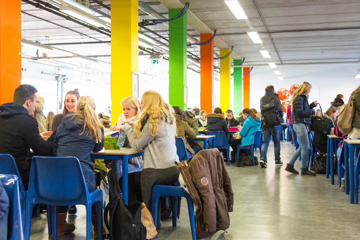 Populaire jongeren die aan tafels zitten in een gebouw en positieve klassen in het vo bevorderen. School en Veiligheid